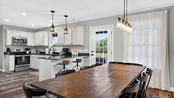 Una cocina moderna con armarios blancos, electrodomésticos de acero inoxidable y una mesa de comedor de madera con sillas.