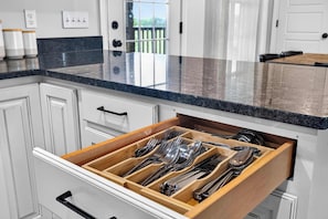 A kitchen with a drawer containing various utensils.