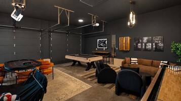 Una habitación con mesa de billar, sofá y mesa de centro.
