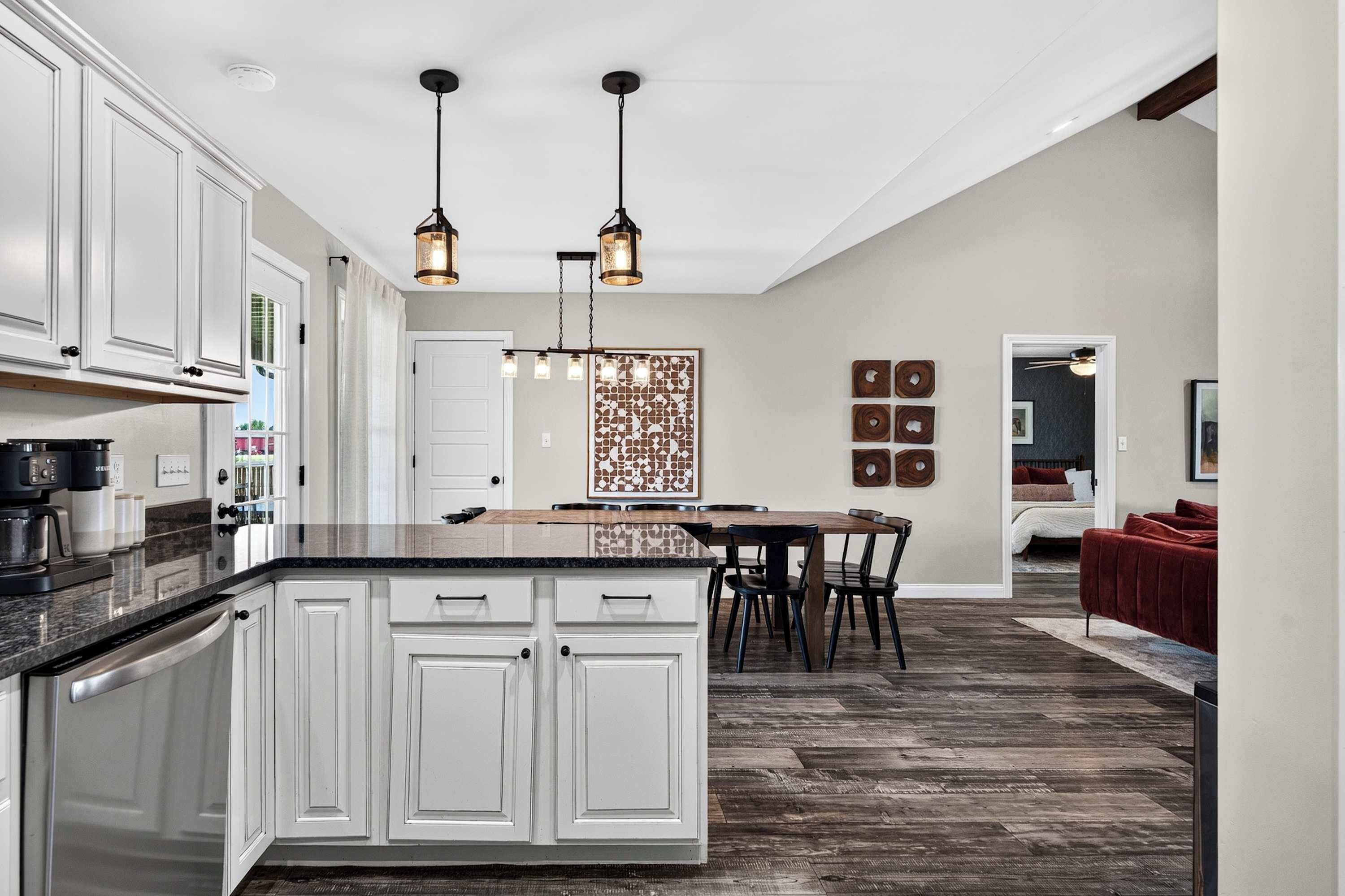 Une cuisine moderne avec des meubles blancs, un îlot central et des luminaires suspendus.