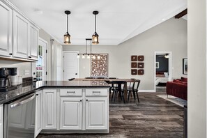 A modern kitchen with white cabinetry, a central island, and pendant lighting.