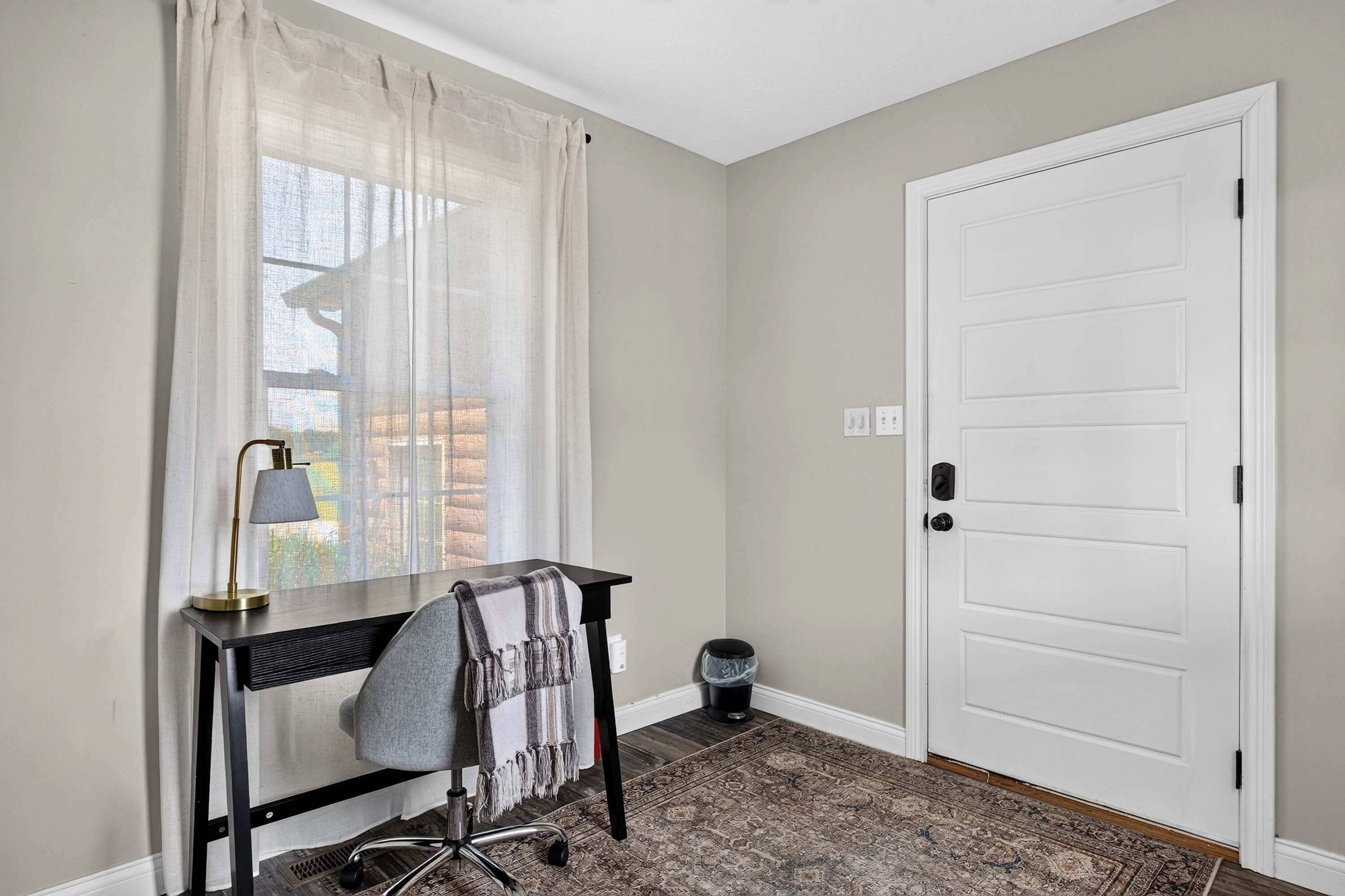 Una stanza con una scrivania, una sedia, una lampada e una porta.