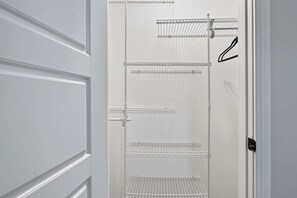A white interior space with a door, a metal shelf unit, and a black hanger.