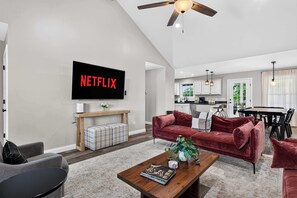 A modern living room with a flat-screen TV, a wooden coffee table, and a red sofa.