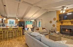 A spacious living area with a fireplace, a sofa, and a dining area with wooden chairs. - Little Creek Cabin- Sky Valley (Dillard)
