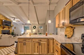 A kitchen with wooden cabinets, a large island, and a built-in oven. - Little Creek Cabin- Sky Valley (Dillard)