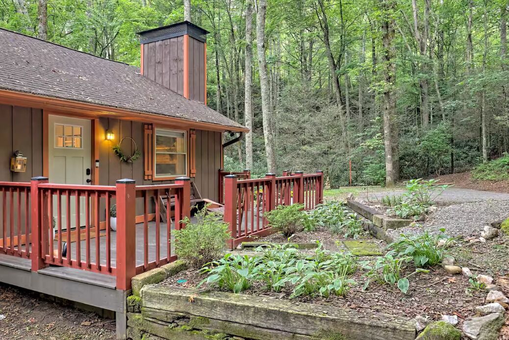 Une cabane dotée d’une véranda, entourée d’une forêt.