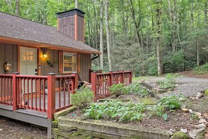 A cabin with a porch, surrounded by a forest.