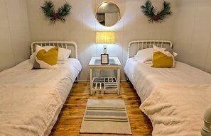 A room with two beds, a bedside table with a lamp, and a small rug on the floor. - Little Creek Cabin- Sky Valley (Dillard)