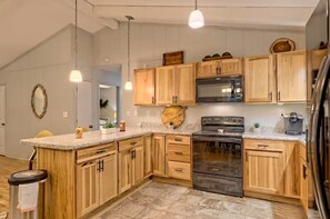 A kitchen with wooden cabinets, a stainless steel stove, and pendant lighting.