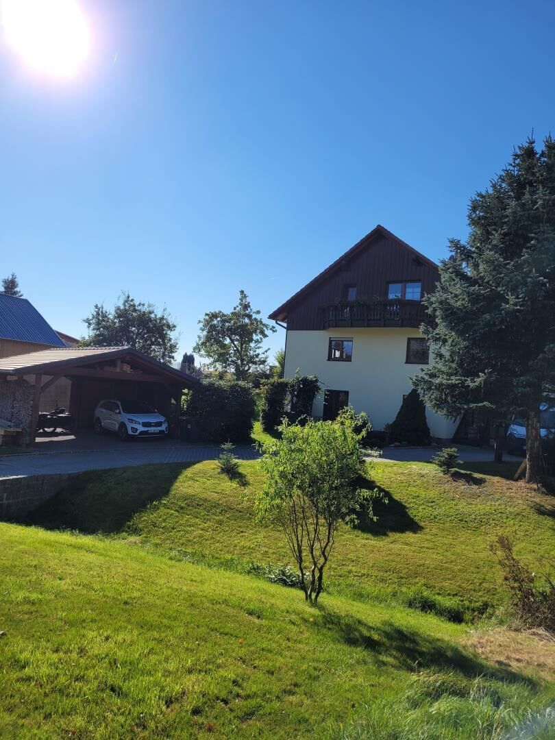 Ein zweigeschossiges Haus mit einer überdachten Auffahrt und einem kleinen Rasen.