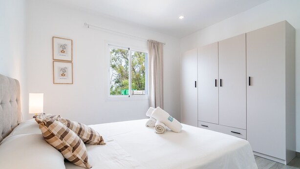 A modern bedroom with a large bed, a wardrobe, and a window with a view of trees. - Cubo's Afrodita House / urban / terrace / air conditioning / free wifi (Alhaurín el Grande)
