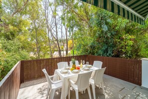 An outdoor dining area with a table set for four, surrounded by a wooden fence, and overlooking a garden with trees and shrubs. - Cubo's Afrodita House / urban / terrace / air conditioning / free wifi (Alhaurín el Grande)