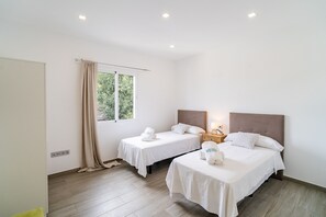 Ein Hotelzimmer mit zwei Einzelbetten, einem Nachttisch, einer Lampe und einem Fenster mit Vorhängen.