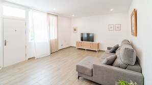 A modern living room with a grey sofa, a TV on a wooden cabinet, and a sliding glass door. - Cubo's Afrodita House / urban / terrace / air conditioning / free wifi (Alhaurín el Grande)
