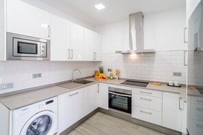 Eine moderne Küche mit weißen Schränken, einem Backofen, einer Mikrowelle und einem Geschirrspüler.