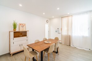A dining area with a wooden table, six chairs, a plant, and a framed picture on a shelf. - Cubo's Afrodita House / urban / terrace / air conditioning / free wifi (Alhaurín el Grande)