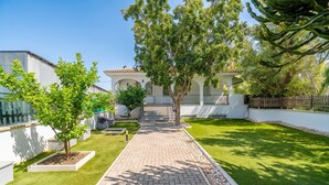 A paved pathway leading to a building with a tiled roof, surrounded by well-maintained grass and trees. - Cubo's Afrodita House / urban / terrace / air conditioning / free wifi (Alhaurín el Grande)