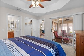 A bedroom with a large bed, a ceiling fan, a walk-in closet, and a sliding glass door leading to a balcony. - Private Courtyard Villa with All-Weather Lanai Near Brownwood (The Villages)