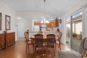 A modern kitchen with wooden cabinets, a dining table with chairs, and a large sliding glass door leading to a patio. - Private Courtyard Villa with All-Weather Lanai Near Brownwood (The Villages)