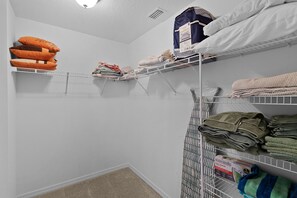Un área de lavandería con estantes que sostienen ropa doblada y toallas.