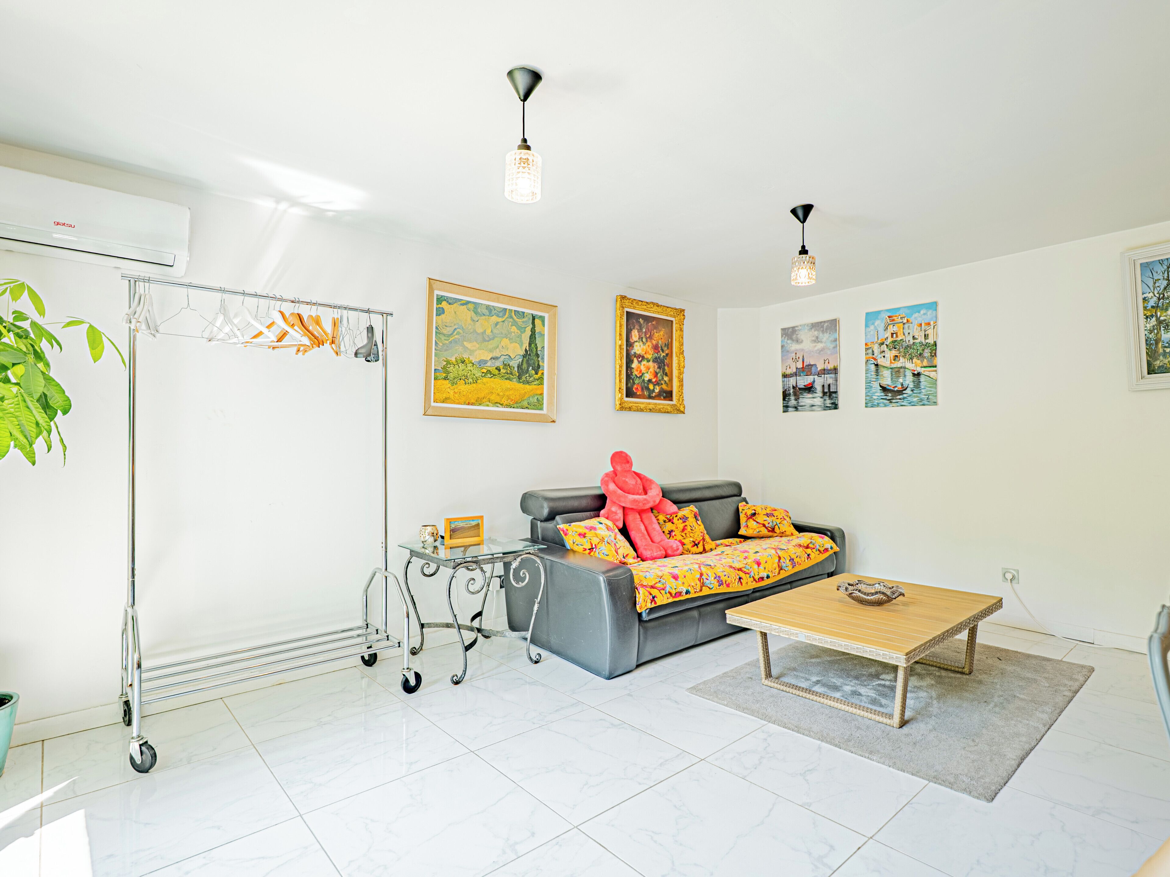 A living room with a grey sofa, a coffee table, and artwork on the walls.