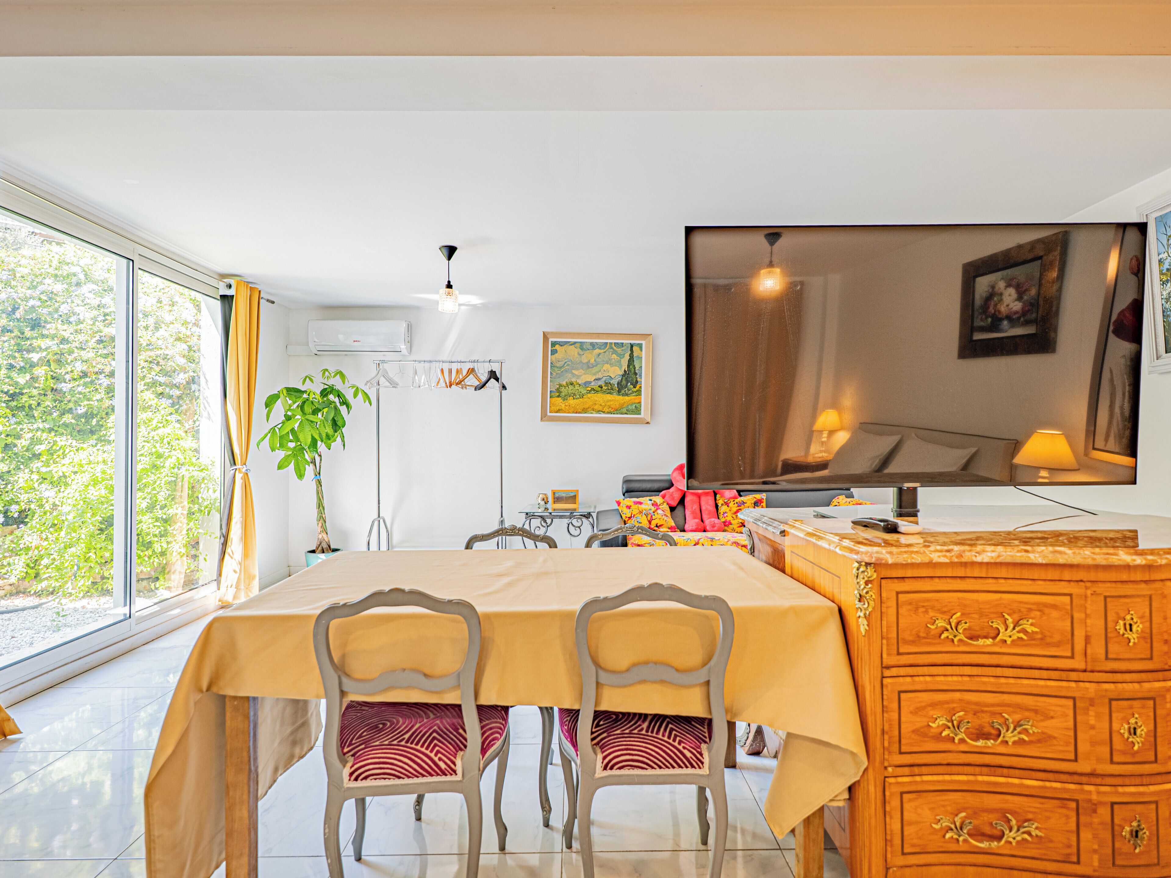 A dining area with a table, chairs, a dresser, and a large window.