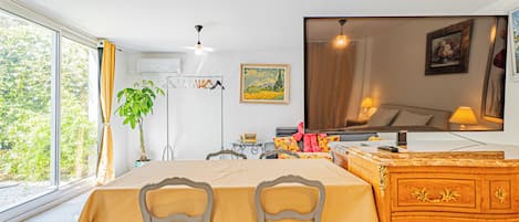 A dining area with a table, chairs, a dresser, and a large window.