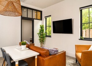 Un salon moderne avec une table blanche, un canapé en cuir et un téléviseur fixé au mur.