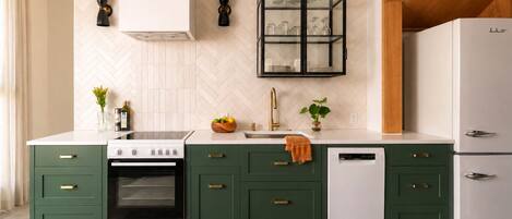 Une cuisine moderne avec des meubles de couleur verte, une cuisinière blanche et un four encastré.