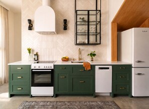 Une cuisine moderne avec des meubles de couleur verte, une cuisinière blanche et un four encastré.