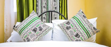 Un lit avec une literie blanche et deux coussins à motifs.