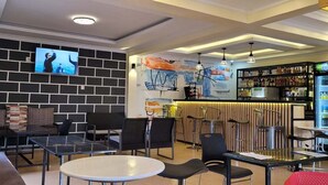 A modern bar area with seating and a television screen. - Adasa Lounge and Suites (Kisumu)