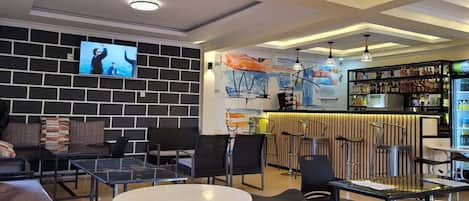 Un área de bar moderna con asientos y una pantalla de televisión.