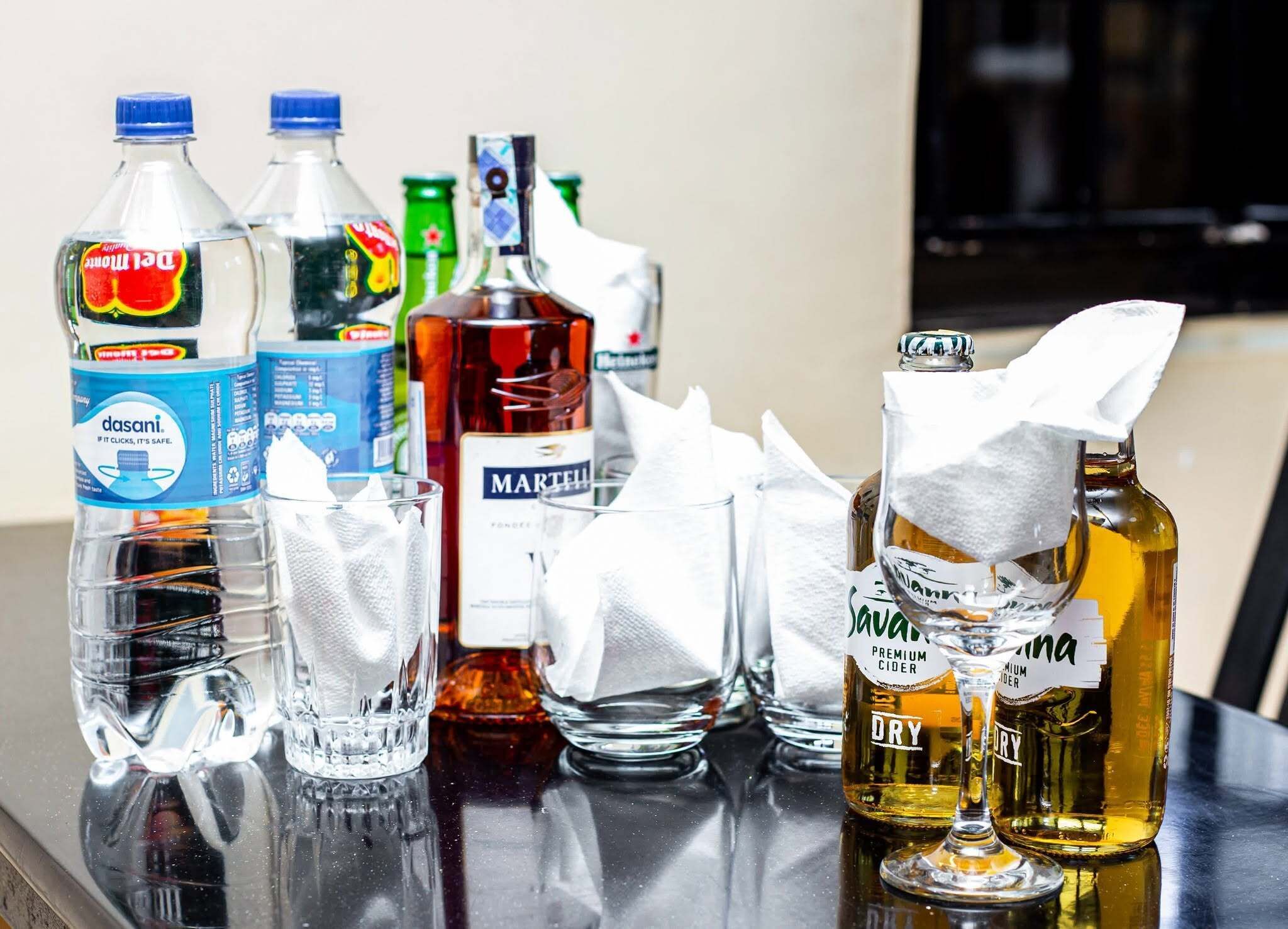 A table with various bottles and glasses, including Dasani water, Martini, and Sava premium cider.