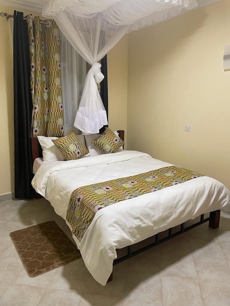 Una cama con dosel, un edredón estampado y una alfombra marrón.