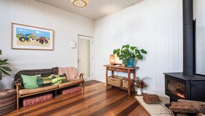 Uma sala de estar aconchegante com um sofá, uma mesa com uma planta, uma lareira e um quadro na parede.