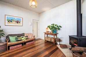 Ein gemütliches Wohnzimmer mit einer Couch, einem Tisch mit einer Pflanze, einem Kamin und einem gerahmten Bild an der Wand.