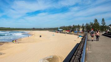 A beach with a clear sky, a sandy shore, and a pedestrian walkway.