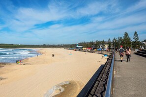 A beach with a clear sky, a sandy shore, and a pedestrian walkway. - Maroubra Escape Beachside Charm and Ocean Glimpses (Maroubra)