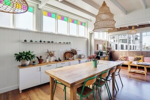 Una cocina amplia con una mesa y sillas de madera, armarios blancos y un ventanal grande con vidrieras de colores.