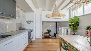 A modern kitchen with white cabinetry, a wooden dining table, and a hanging light fixture.