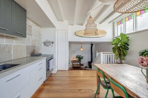 Una cocina moderna con armarios blancos, una mesa de comedor de madera y una lámpara colgante.