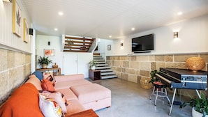 Uma sala de estar com sofá, piano, televisão e escada.