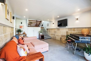 Ein Wohnzimmer mit einer Couch, einem Klavier, einem Fernseher und einer Treppe.