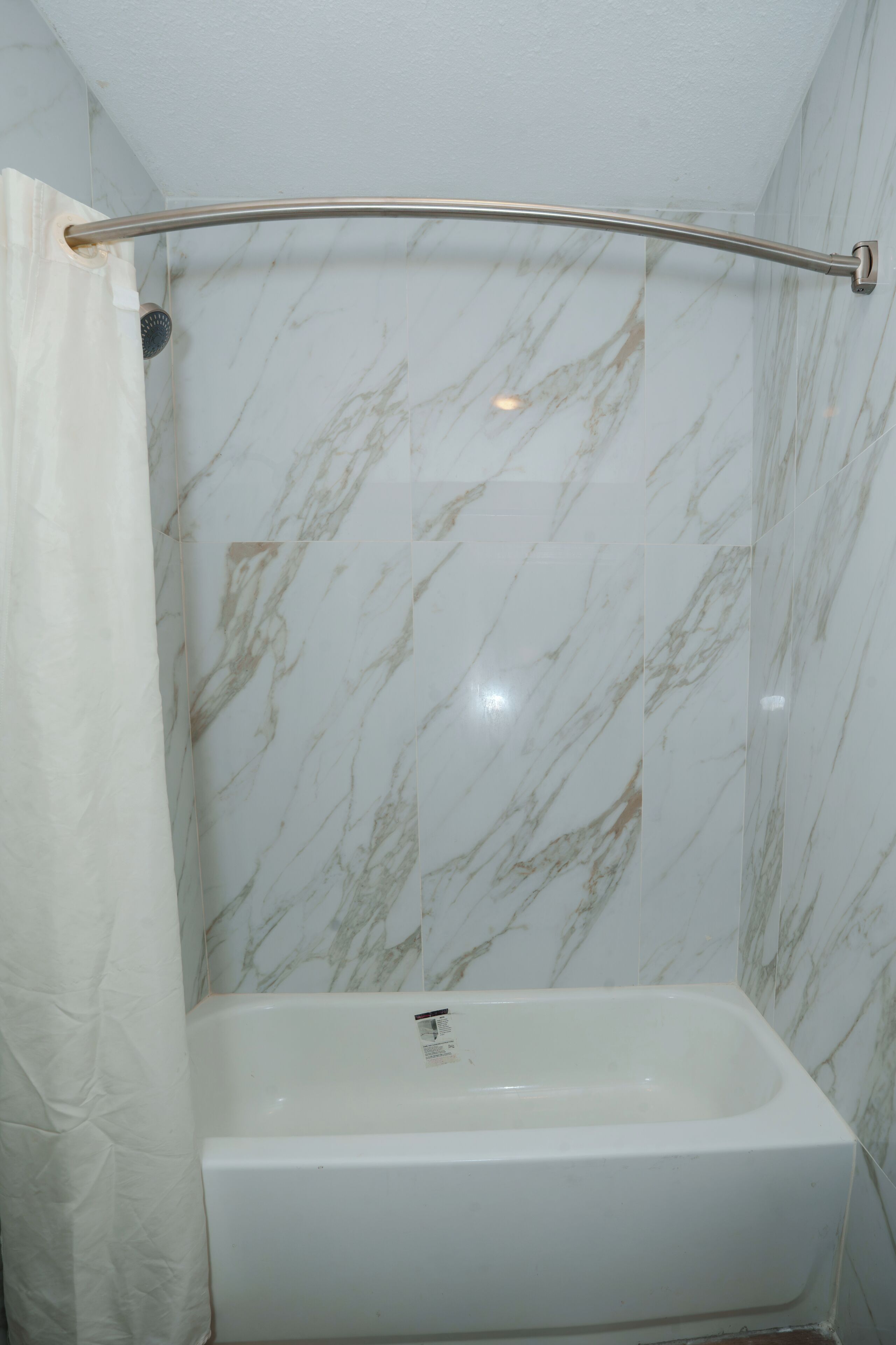 A bathroom with a shower, a bathtub, and marble walls.