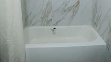 A bathroom with a shower, a bathtub, and marble walls.