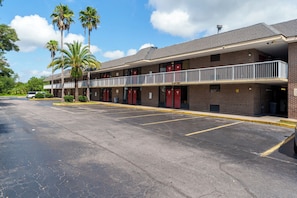 A multi-story motel with a parking lot, featuring a balcony on the second floor. - RiverCity inn (Jacksonville)