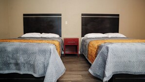 Habitación de hotel con dos camas, cada una con cabecero, mesita de noche y cajón.