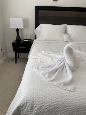 A neatly made bed with a white comforter and a folded white towel. - Luxury home in the heart of Roseville, CA. Resort-Style salt water pool and more (Roseville)